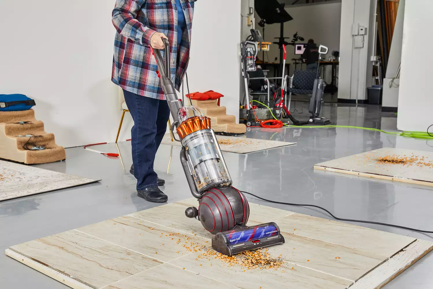 Person cleaning food from a tile floor using the Dyson Ball Animal 3 Extra 